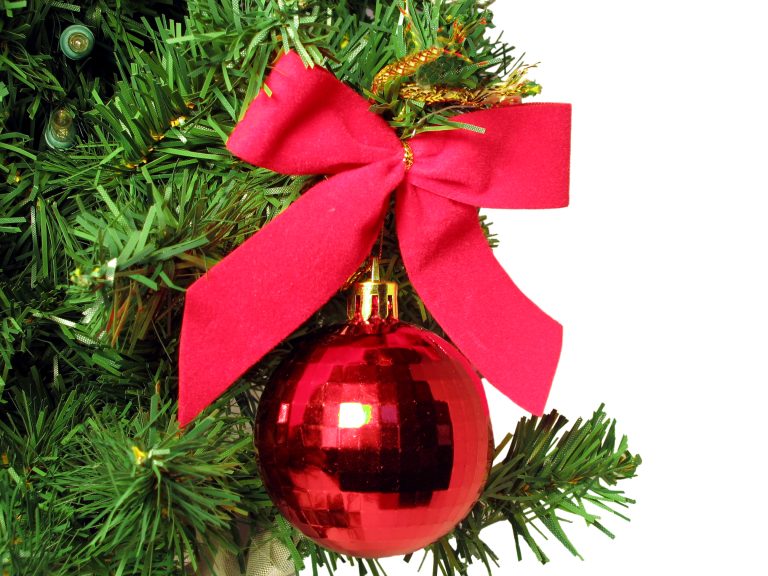 Red bow and round ornament hanging from Christmas Tree