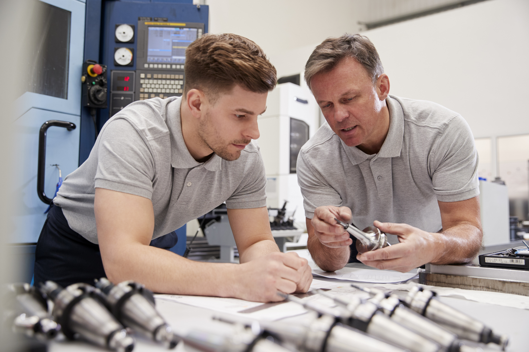 innovation - Engineer Showing Apprentice How To Measure CAD Drawings