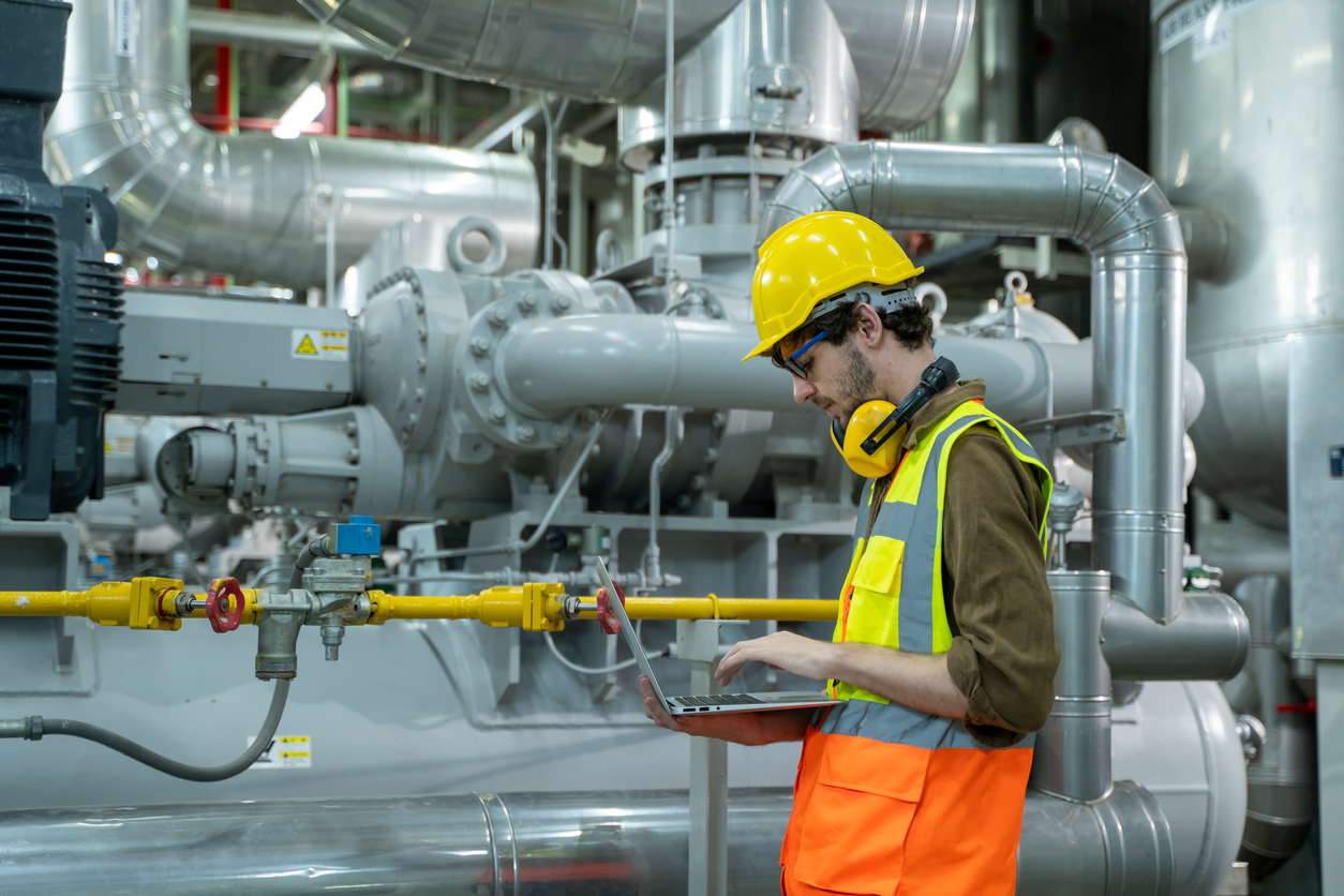 Engineer using laptop computer working in thermal power plant at industry factory.